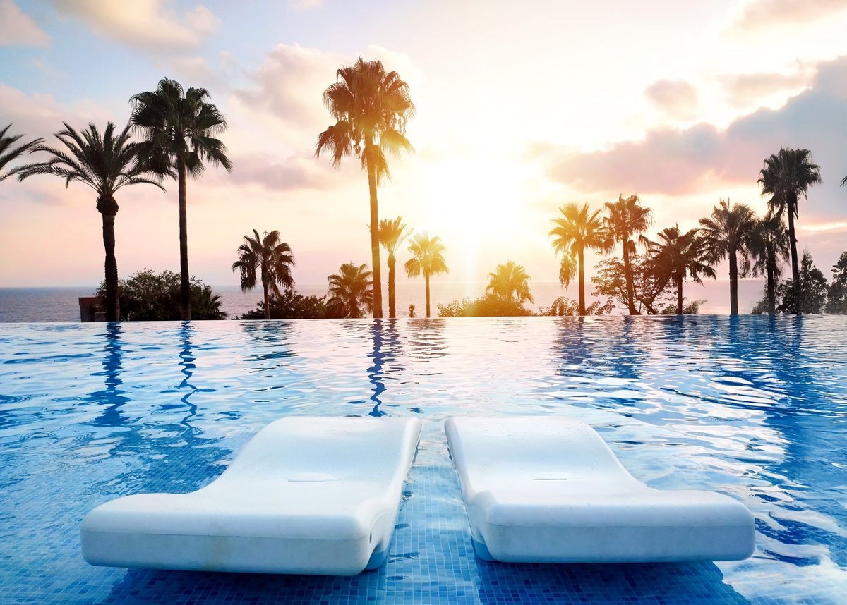 Tranquil sunset over infinity pool with palm trees